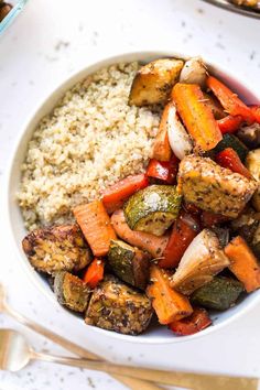 a white bowl filled with rice, carrots and tofu pieces on top of it