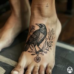 a black bird sitting on top of a person's foot with leaves and flowers around it