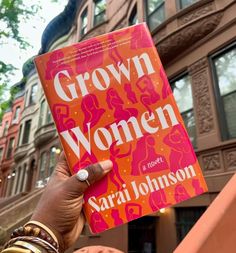 a person holding up a book in front of a building with the words grown women written on it