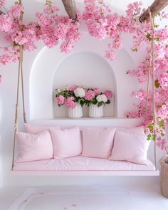 pink flowers are in white vases and on the wall, near a swing bed