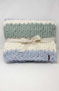 two crocheted blankets with a ribbon tied around the edges, stacked on top of each other