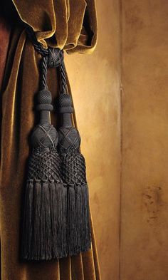 two tassels hanging from the side of a curtain in front of a wall