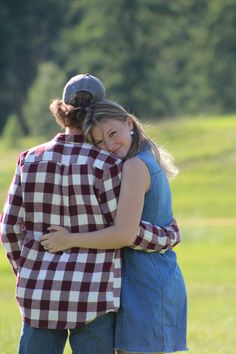 two people hugging each other in a field