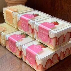 four plastic containers filled with strawberries on top of a wooden table