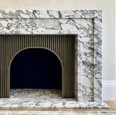 a white marble fireplace with an arch in the middle and a black door at the end