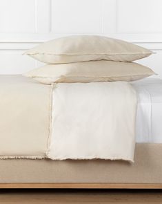 two pillows on top of a bed with white sheets