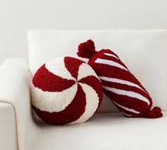 a red and white striped pillow sitting on top of a white couch next to a candy cane