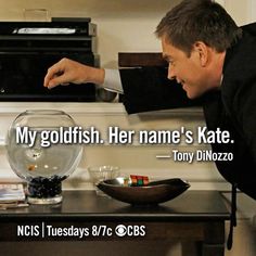 a man pointing at a bowl on top of a table next to a microwave oven with the words, my goldfish her name's kate