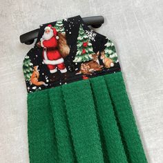 a pair of green towels with santa claus on it and other christmas items hanging from the handles