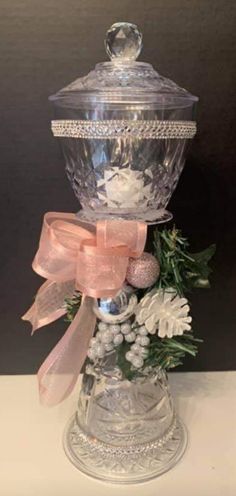 a clear glass container with pink ribbon and flowers in it