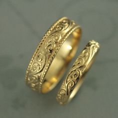 two gold wedding bands with intricate designs on them