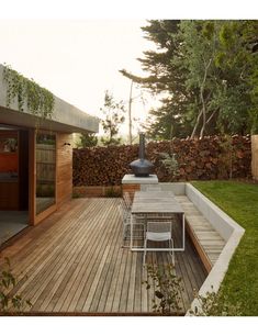 a table and chairs on a wooden deck in the middle of a yard with trees