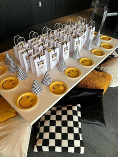 a table topped with paper bags filled with yellow smiley face plates and black and white checkered napkins