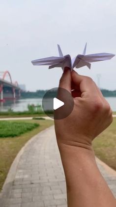 someone is holding an origami airplane in their hand and pointing it at the camera