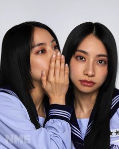 two young women are posing for the camera with their hands on their faces and one is covering her face