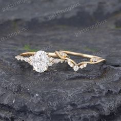 two gold rings with diamonds sitting on top of a rock