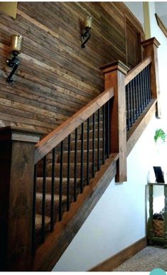 a wooden stair case next to a table with a plant on it and a clock hanging from the wall