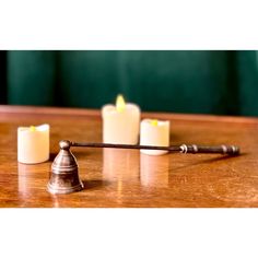 three candles are sitting on a table next to a small metal bell and candle holder