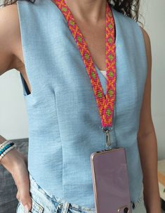 a woman holding a cell phone with a lanyard around her neck and an apple logo on it