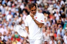 a man in white holding a tennis racquet and talking on a cell phone