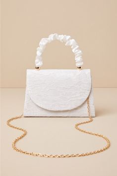 There is no easier way to elevate your springtime looks than with the Lulus Exceptional Class Ivory Lace Ruched Handle Mini Handbag! Chic floral lace (atop woven satin) shapes this cute mini bag that boasts a structured silhouette, a ruched satin top handle with gold beaded accents, and a flat bottom design. The front flap features a hidden magnetic closure that opens to reveal a lined, compact interior with a sidewall pocket. Attach the removable gold chain strap when you want a crossbody look! Lined. Bag measure 7. 75" wide, 5. 25" tall, and 2. 25" deep. 3. 25" drop. Chain measures 44" long. 100% Polyester. Imported. Lulus | Exceptional Class Ivory Lace Ruched Handle Mini Handbag | 100% Polyester. Elegant Spring Bags With Detachable Handle, Spring Party Bags With Pearl Handle, Rectangular Shoulder Bag For Spring Events, Feminine Formal Bags For Spring, Spring Evening Bags, Elegant Summer Evening Bag With Detachable Handle, Spring Evening Bag With Detachable Strap, Elegant White Clutch For Spring, Elegant White Spring Clutch