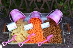 there are many different types of snacks on the table with pink cups and straws