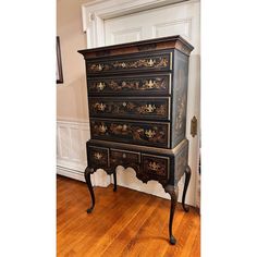 an old black dresser with ornate carvings on it's drawers and legs, in a room