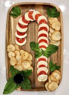 a wooden platter with crackers, tomatoes and mozzarella