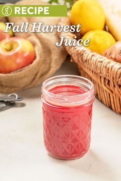 a jar filled with red liquid sitting on top of a table next to some fruit