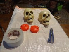 two skulls sitting on top of a table next to a roll of tape and scissors