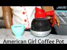 the american girl coffee pot is next to a cup and a doll's hand