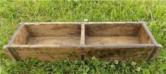 a wooden box sitting in the grass on top of some green grass with one section missing