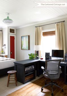 a bedroom with a bed, desk and computer