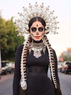 a woman with skeleton makeup and headdress in the street