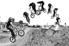 a black and white photo of a man on a bike doing tricks in the air