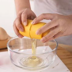 a person pouring cheese into a glass bowl