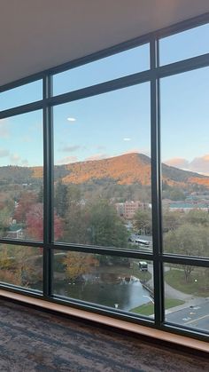 an empty room with large windows looking out at the mountains and parking lot in front of it