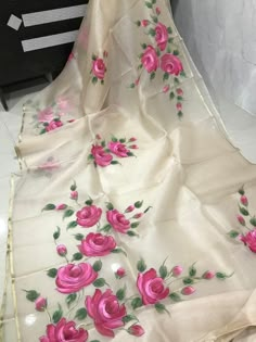 a white and pink flowered table cloth with green leaves on the edges, sitting on a black chair