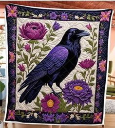 a black bird sitting on top of a table next to purple flowers