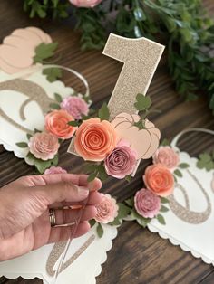 a person is holding flowers in front of the number one cake topper on a table