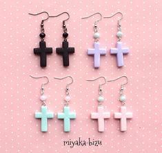 four pairs of cross earrings are shown on a pink and white polka dot background with beads