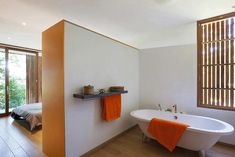 an orange towel hanging on the wall next to a bathtub in a white bathroom