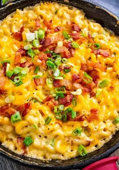 a skillet filled with macaroni and cheese covered in bacon, scallions and green onions