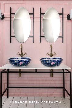 two sinks with mirrors above them in a pink wall bathroom, one blue and the other white