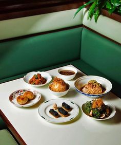 a table topped with plates of food on top of a white countertop next to a potted plant