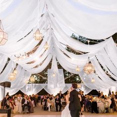 a bride and groom share their first dance under the draping at their wedding reception