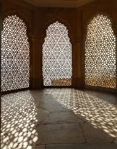 the sun shines through three arched windows in an ornately designed room with stone flooring