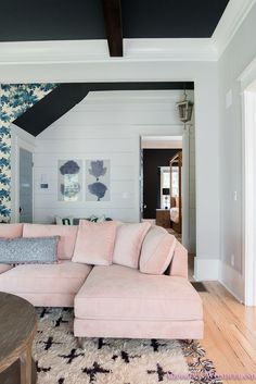 a living room with pink couches and floral wallpaper on the walls, along with rugs