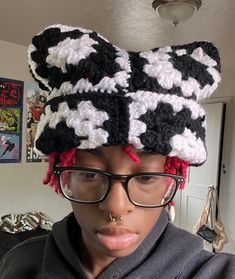 a woman wearing glasses and a black and white crocheted hat