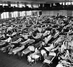 an old black and white photo of many beds in a room filled with people sleeping